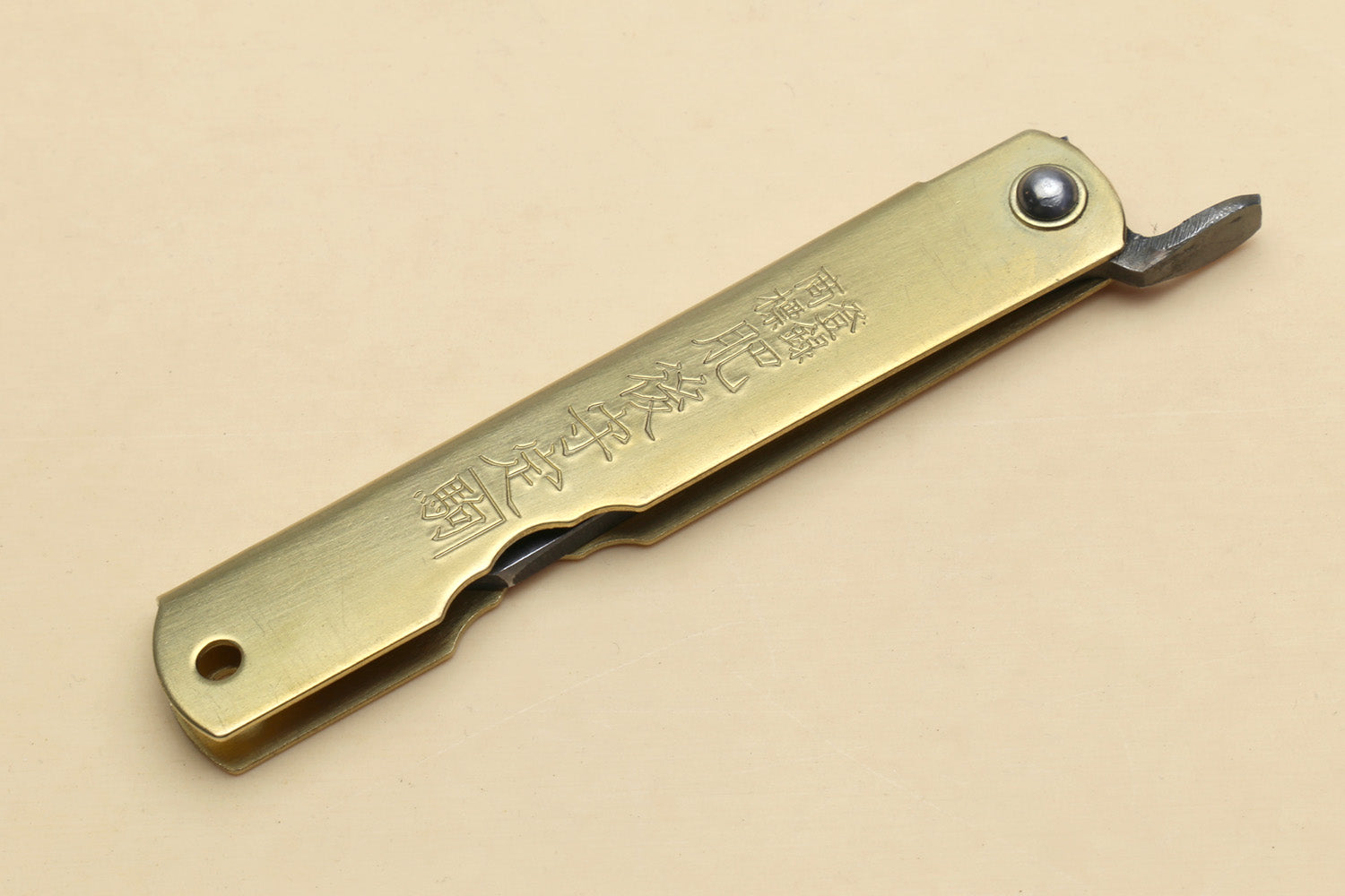 Kiridashi pocket knife with gold handle and visible rivet, single pointed blade