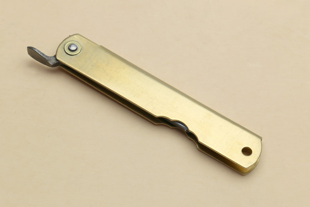 Kiridashi pocket knife with gold handle, metal clip, and extended pointed blade