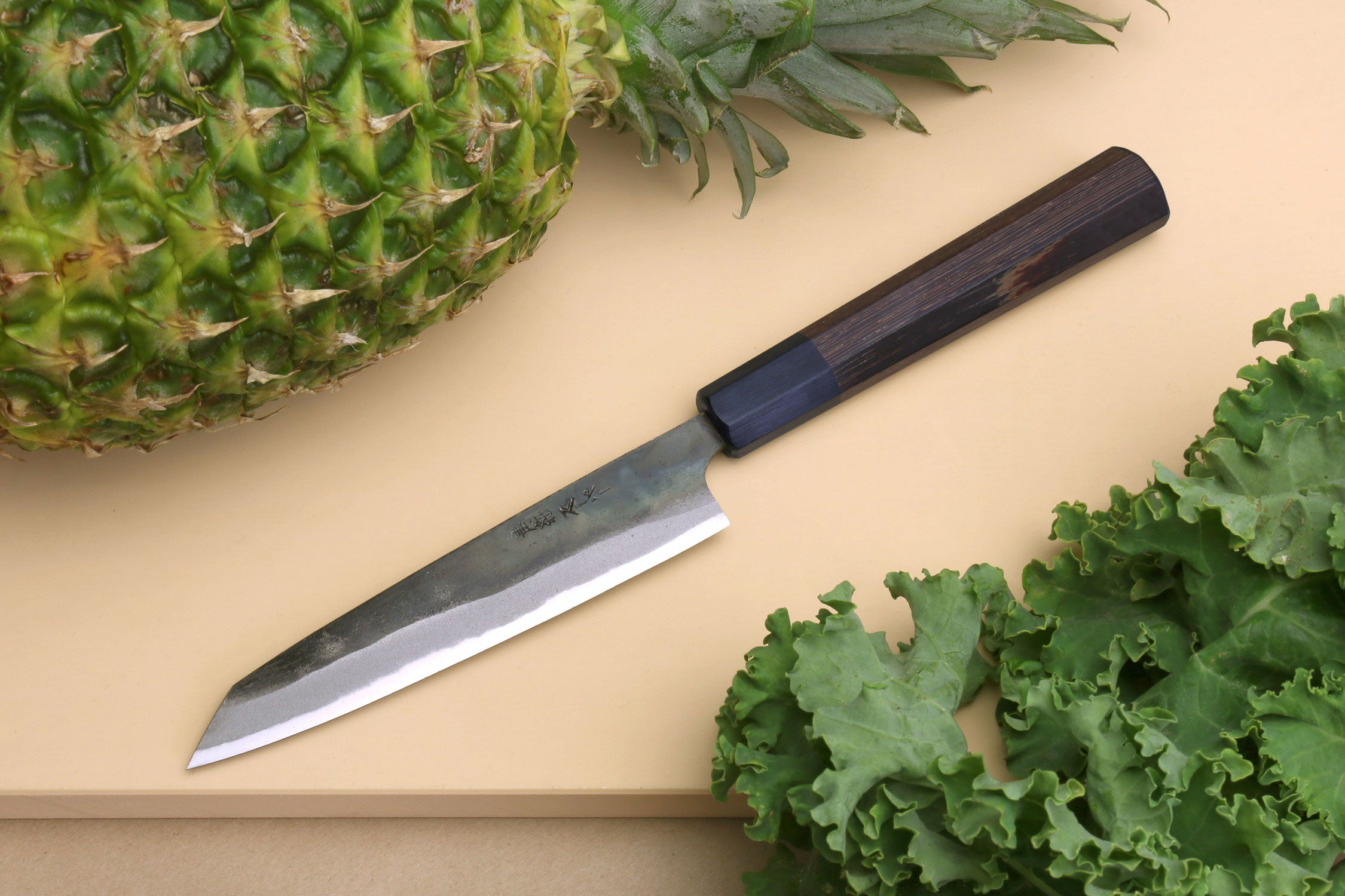 Petty utility knife with kurouchi-finished steel blade and dark shitan wood handle.