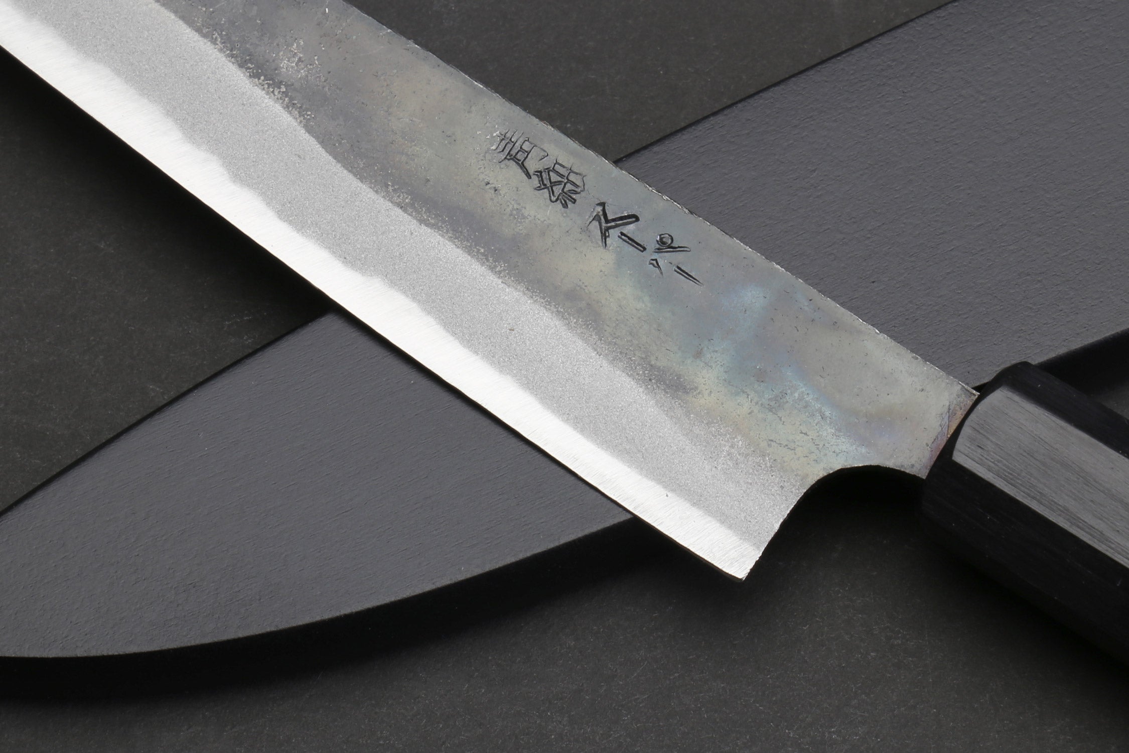 Petty utility knife blade with engraved text on darkened steel, dark shitan handle.