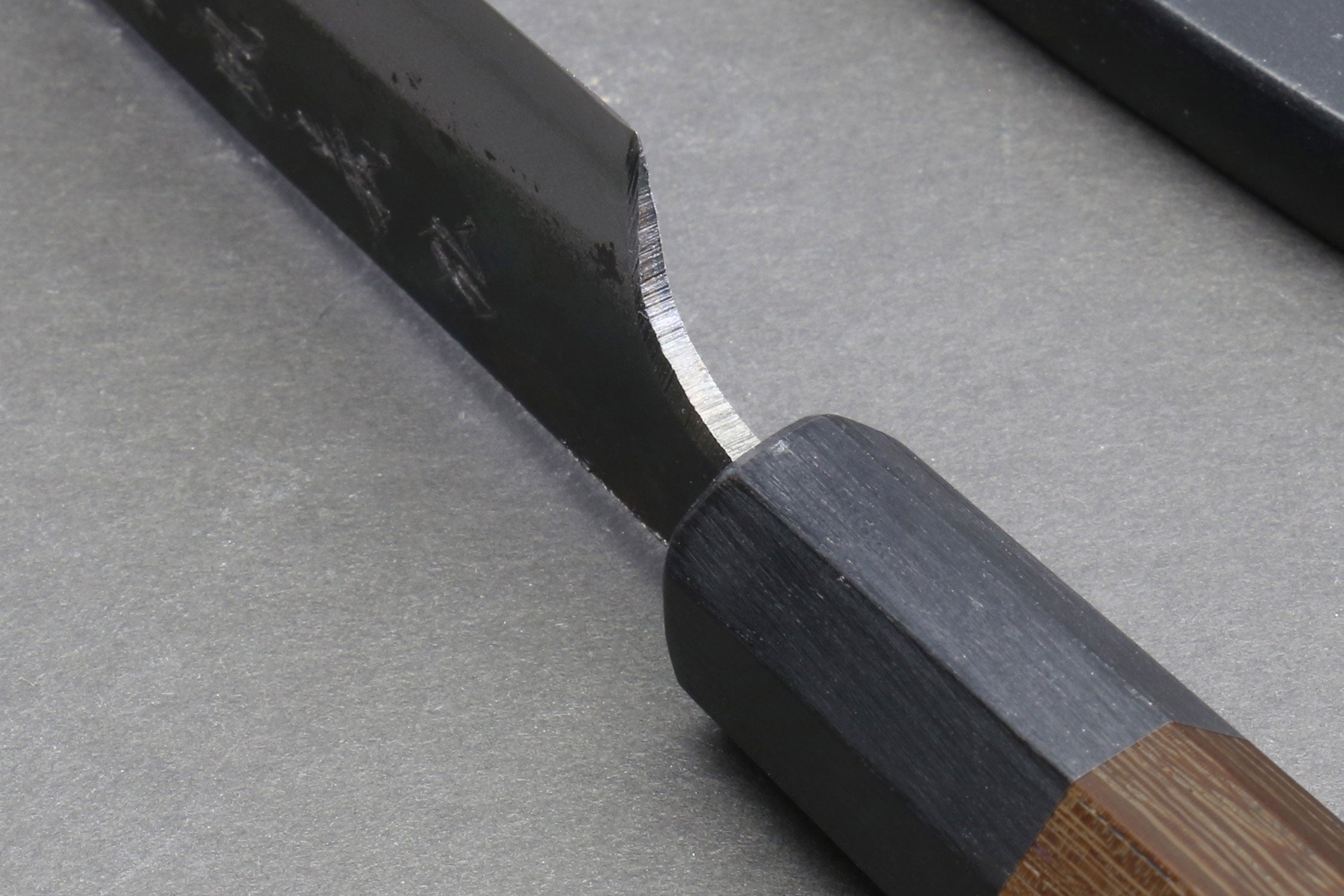 Dark shitan wood handle with partially visible steel blade and engraved markings.