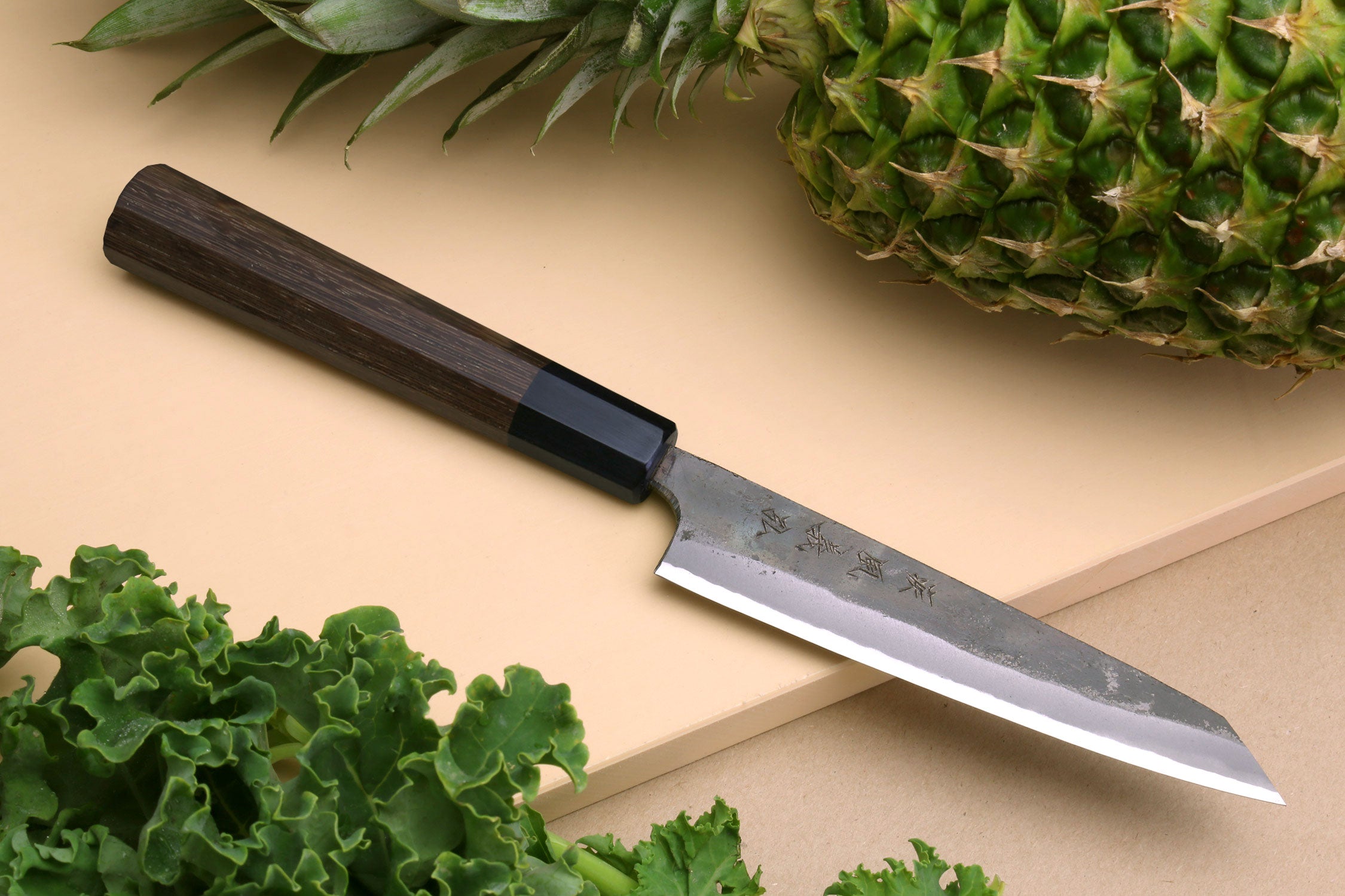 Petty utility knife with kurouchi-finished steel blade and dark shitan wood handle.