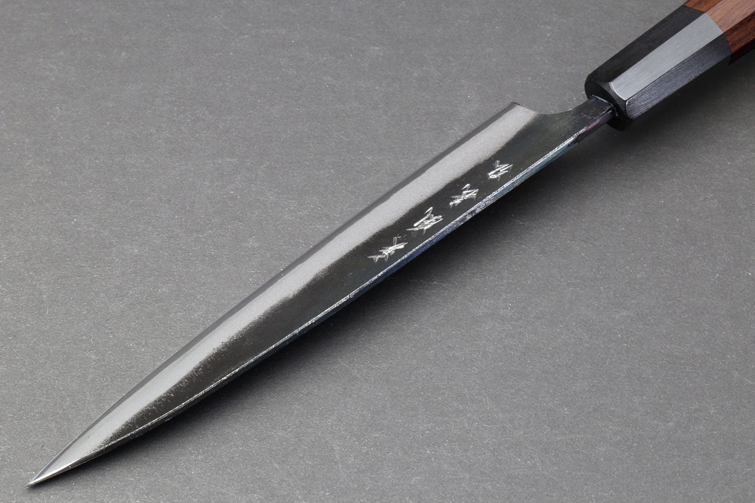 Petty utility knife with pointed tip, kurouchi blade, and dark wood handle