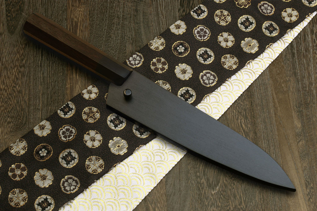 Petty utility knife with dark shitan wood handle and kurouchi blade on patterned cloth