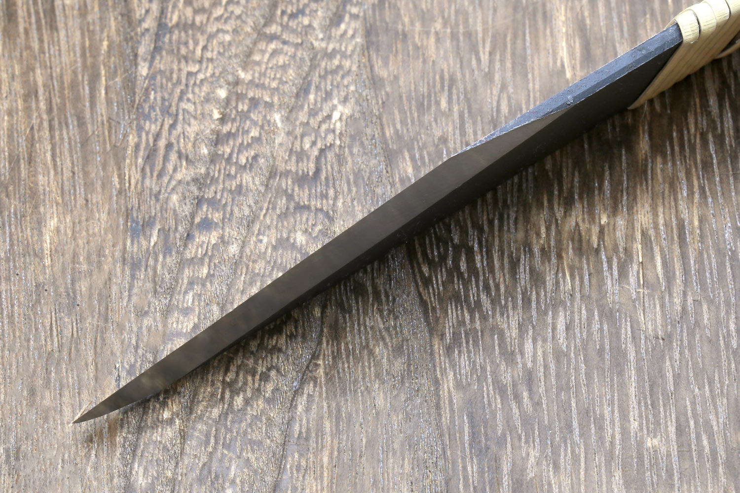Kiridashi utility knife side view with dark steel blade and ribbed light wooden handle
