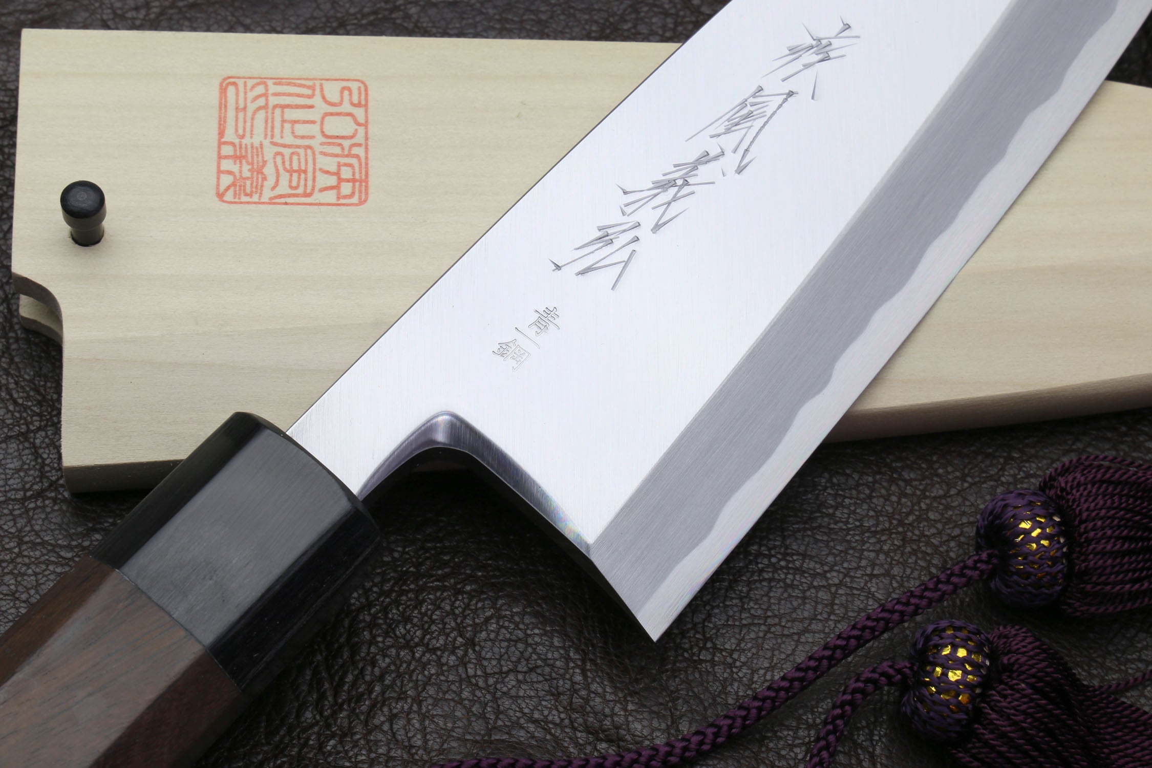 Deba knife blade close-up with etched markings and dark bolster