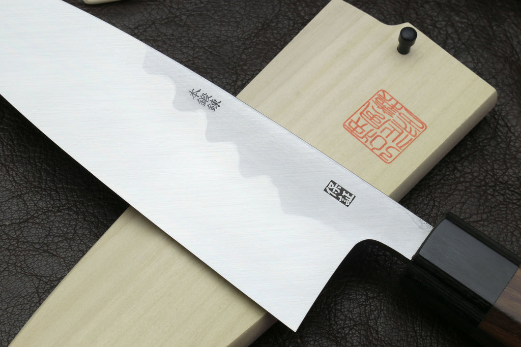 Japanese deba knife with white blade, dark handle, and light wooden saya