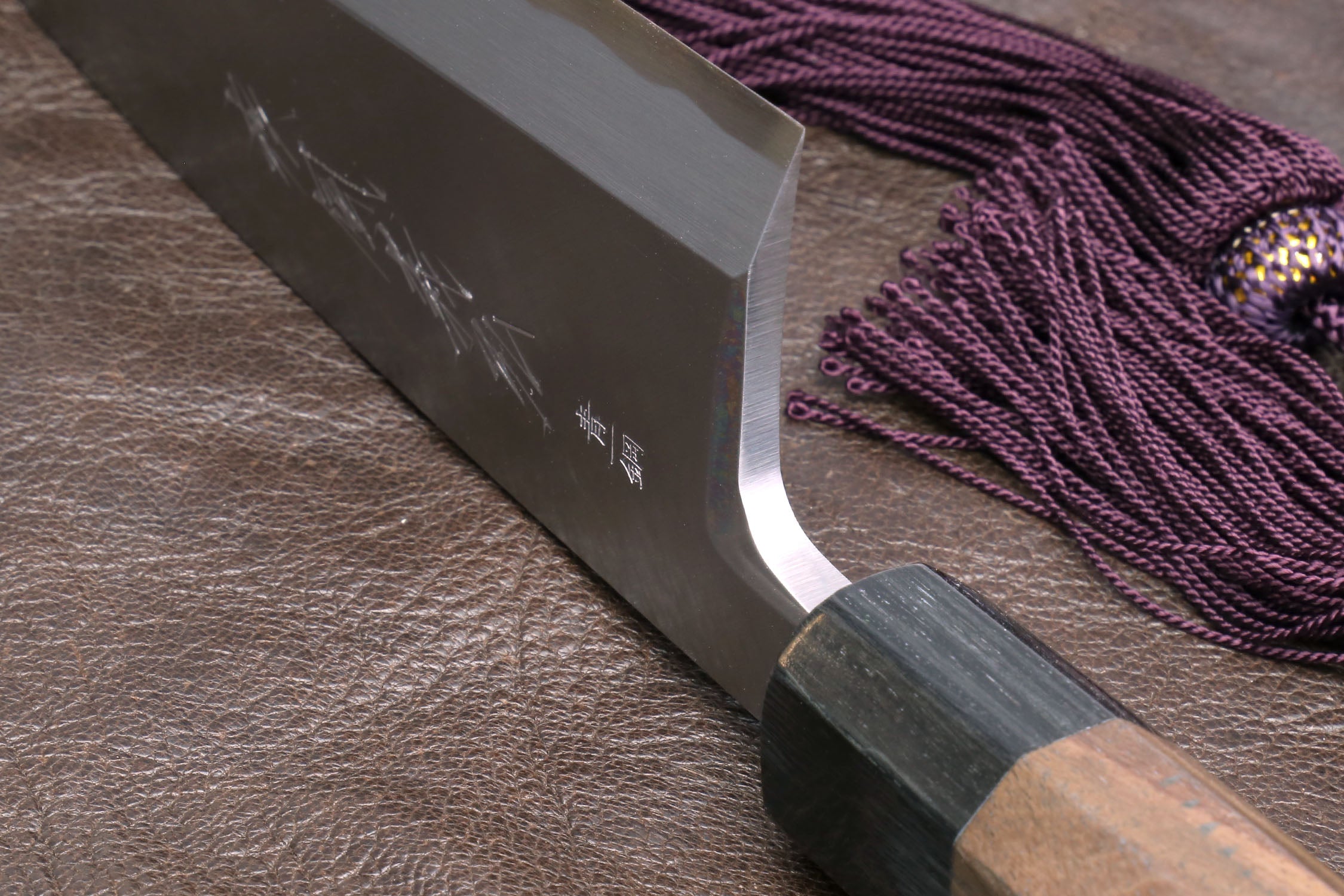 Deba knife with dark spine, white edge, and dark shitan handle on leather