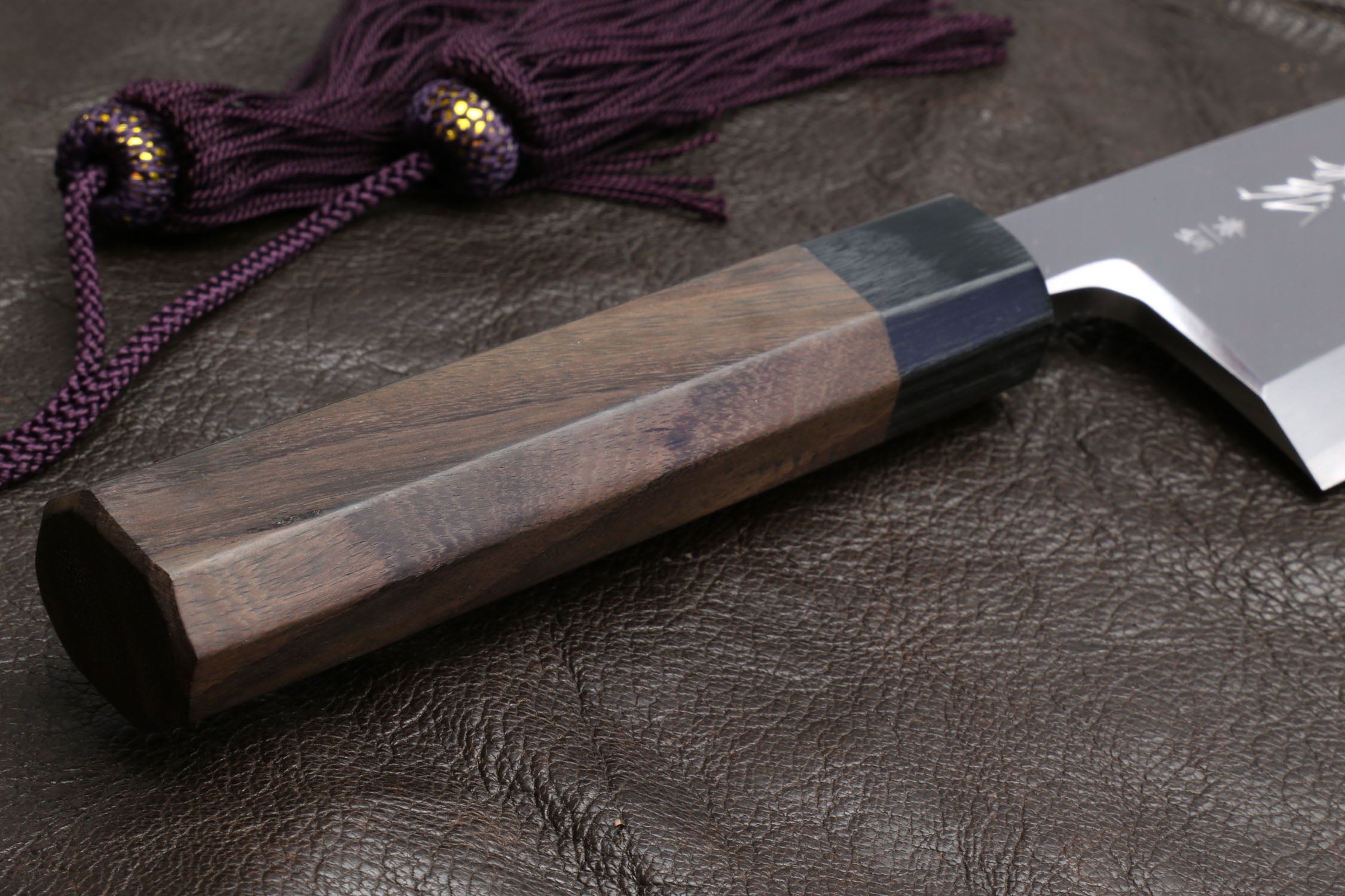 Deba knife with shitan handle and purple cord over the light wooden saya