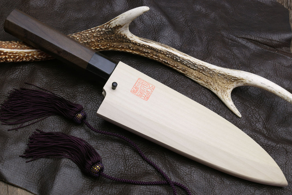 Deba knife with white blade, dark handle, and horn-style decorative guard