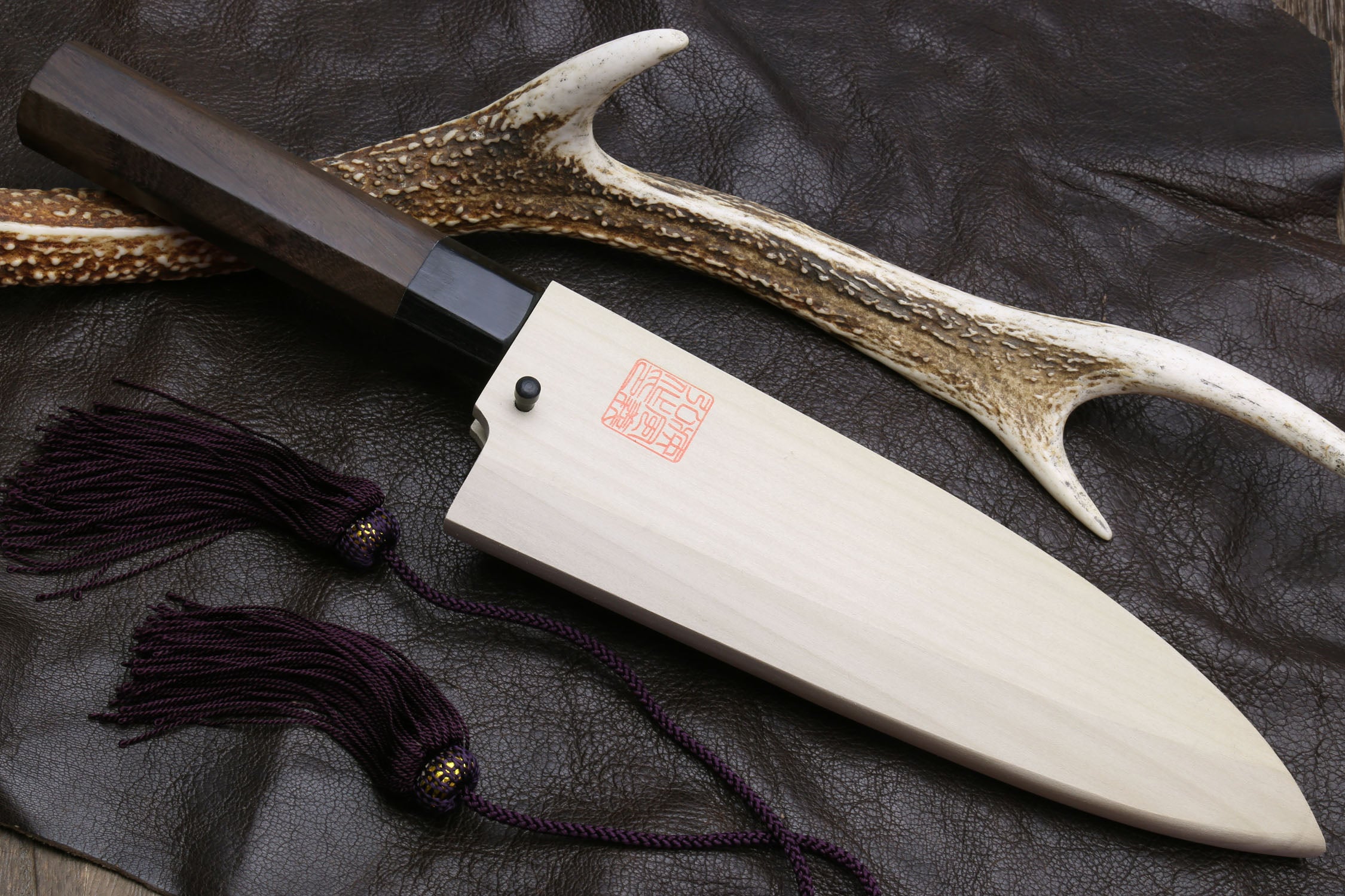 Deba knife with white blade, dark handle, and horn-style decorative guard