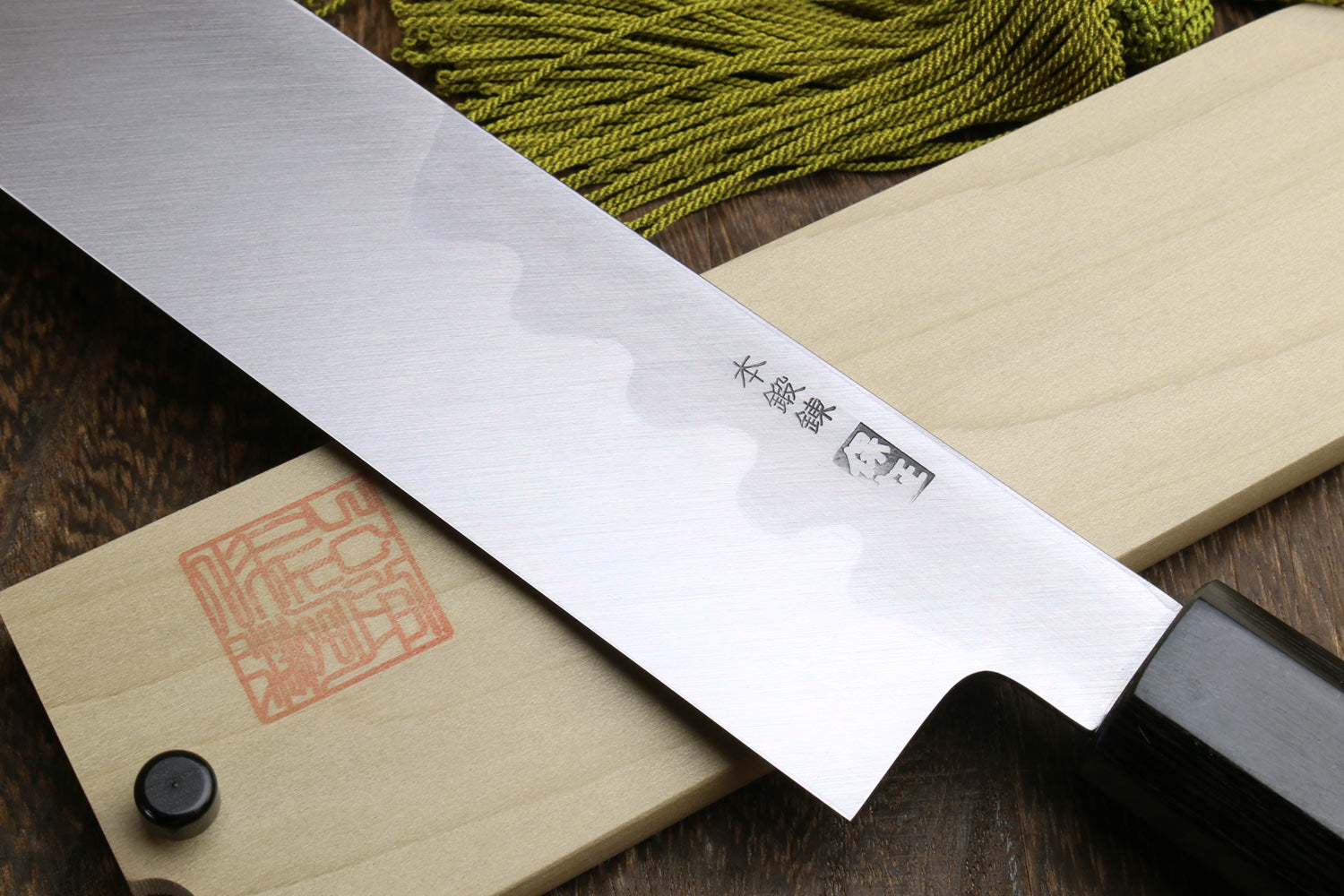 Japanese single-edged vegetable knife, angled close-up of silver blade with engraved kanji