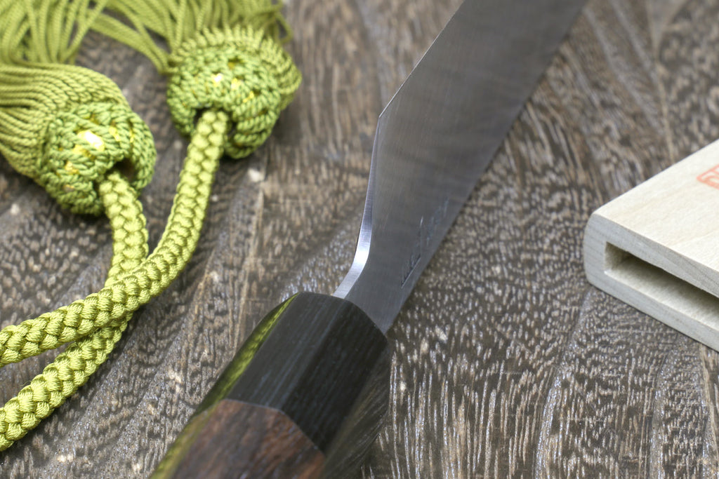 Japanese single-edged vegetable knife with dark wood handle and green tassel cord