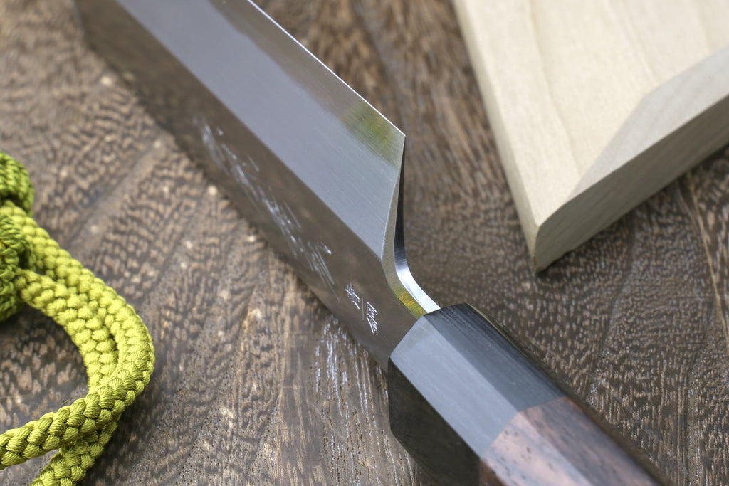 Japanese single-edged vegetable knife, close-up of blade tip beside wooden saya