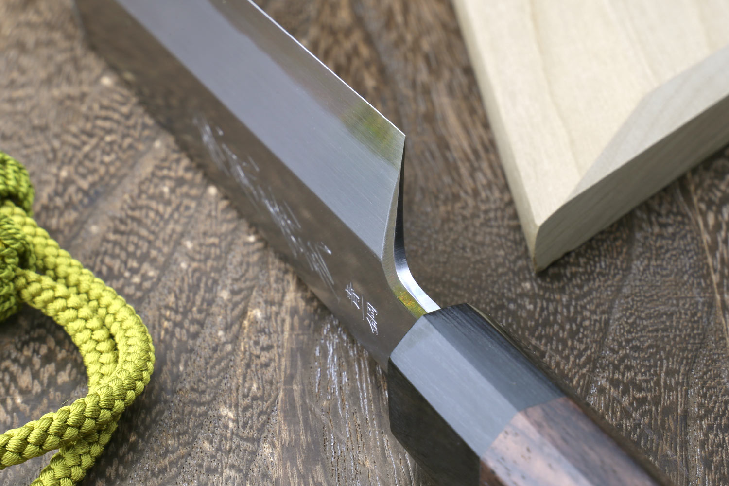 Japanese single-edged vegetable knife, close-up of blade tip beside wooden saya