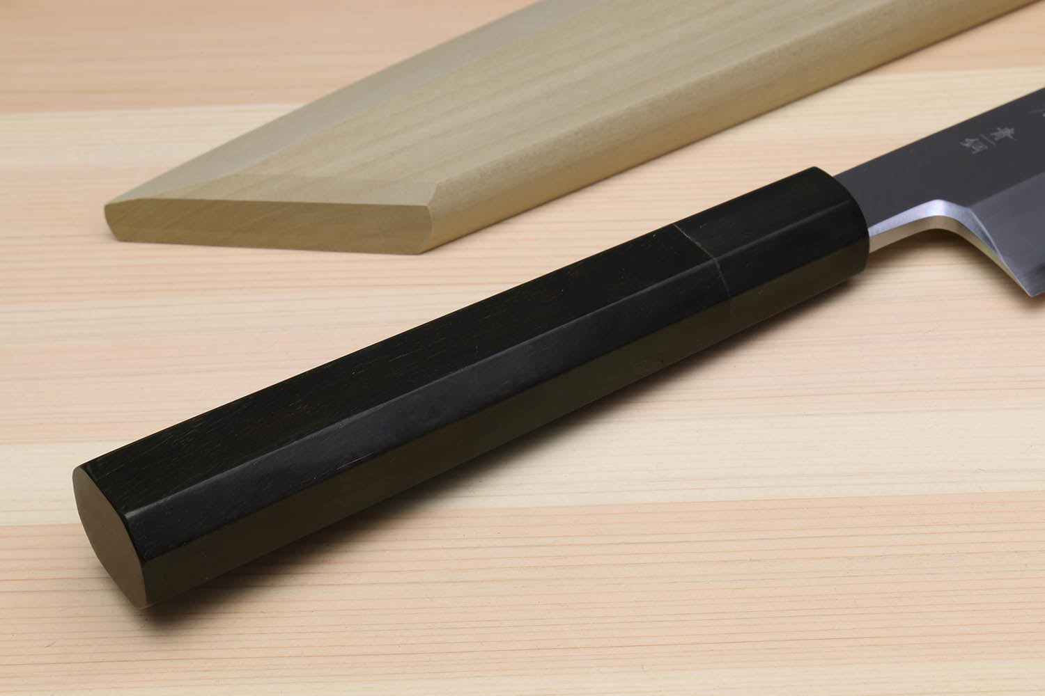 Multipurpose chef knife with black handle and silver blade on light wood board