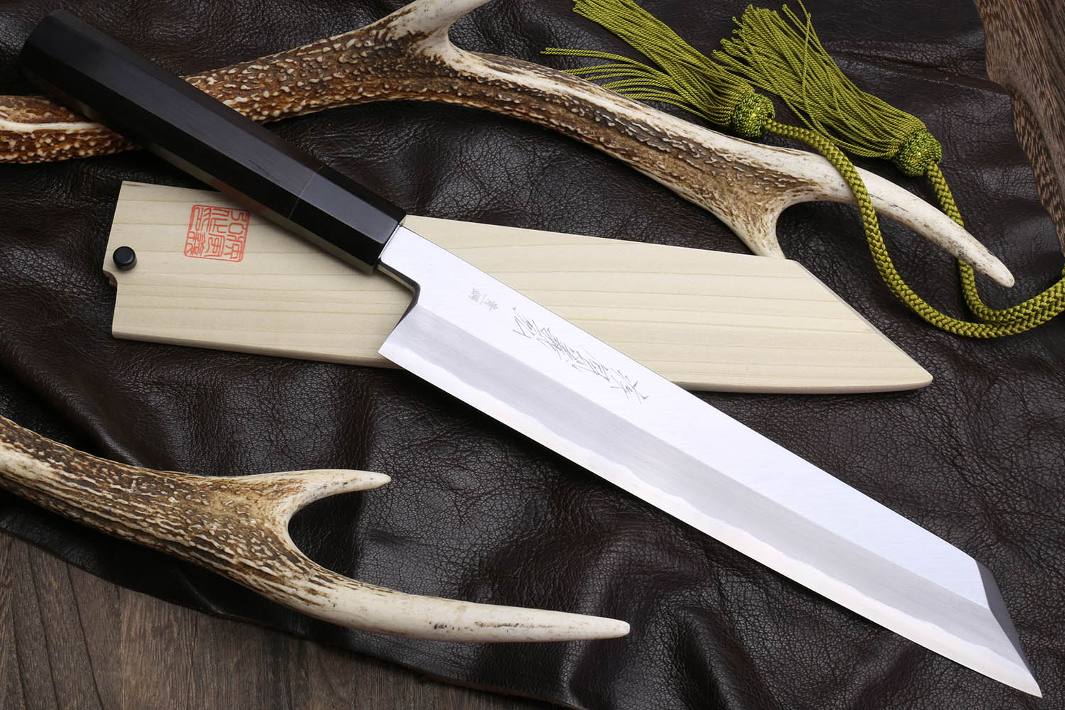 Multipurpose chef knife with silver blade, black handle, light wood sheath