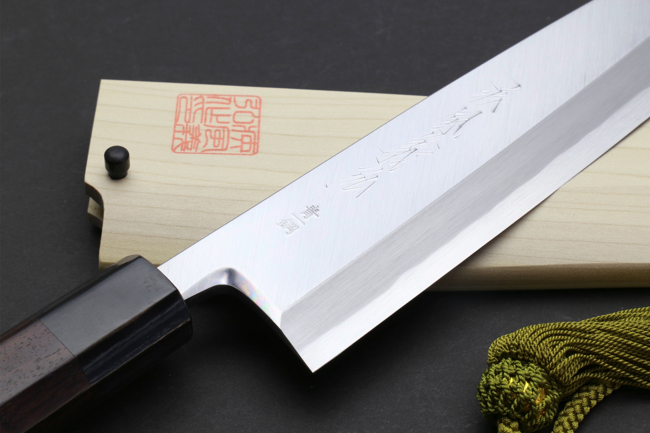 Japanese chef knife with engraved blade and dark handle, with light saya