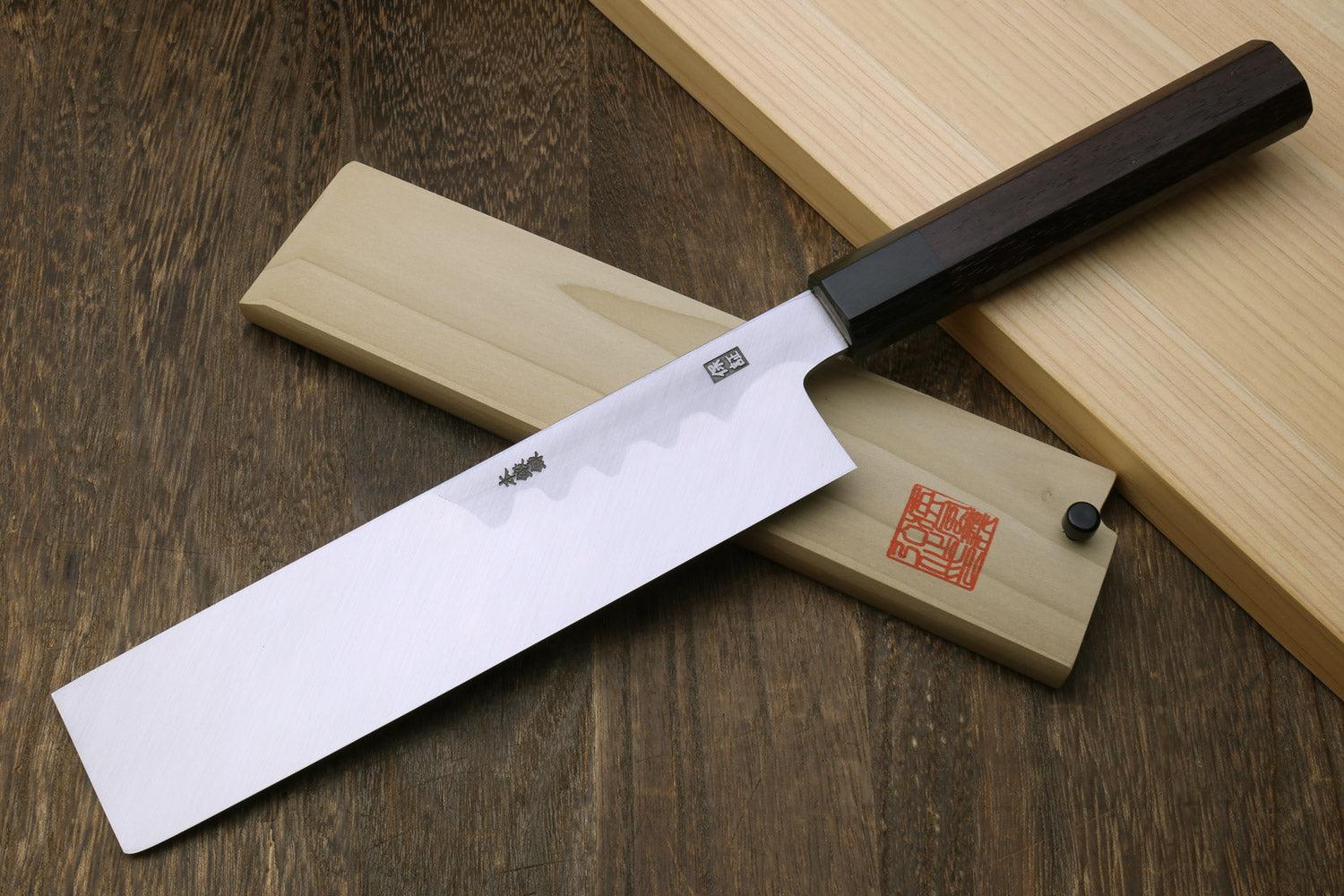 Japanese vegetable knife with pale steel blade and dark handle, light wooden sheath
