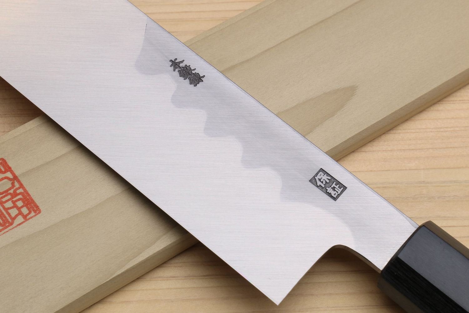 Japanese vegetable knife close-up of pale blade with curved cutout and dark handle