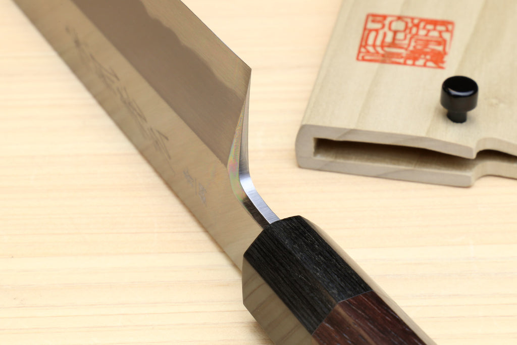 Japanese vegetable knife showing pale blade edge and dark rosewood handle junction