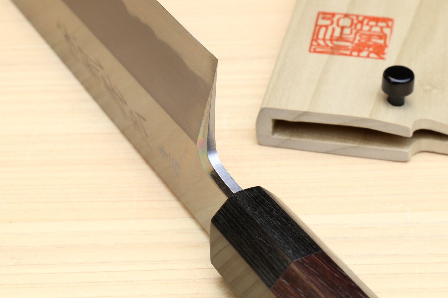 Japanese vegetable knife showing pale blade edge and dark rosewood handle junction