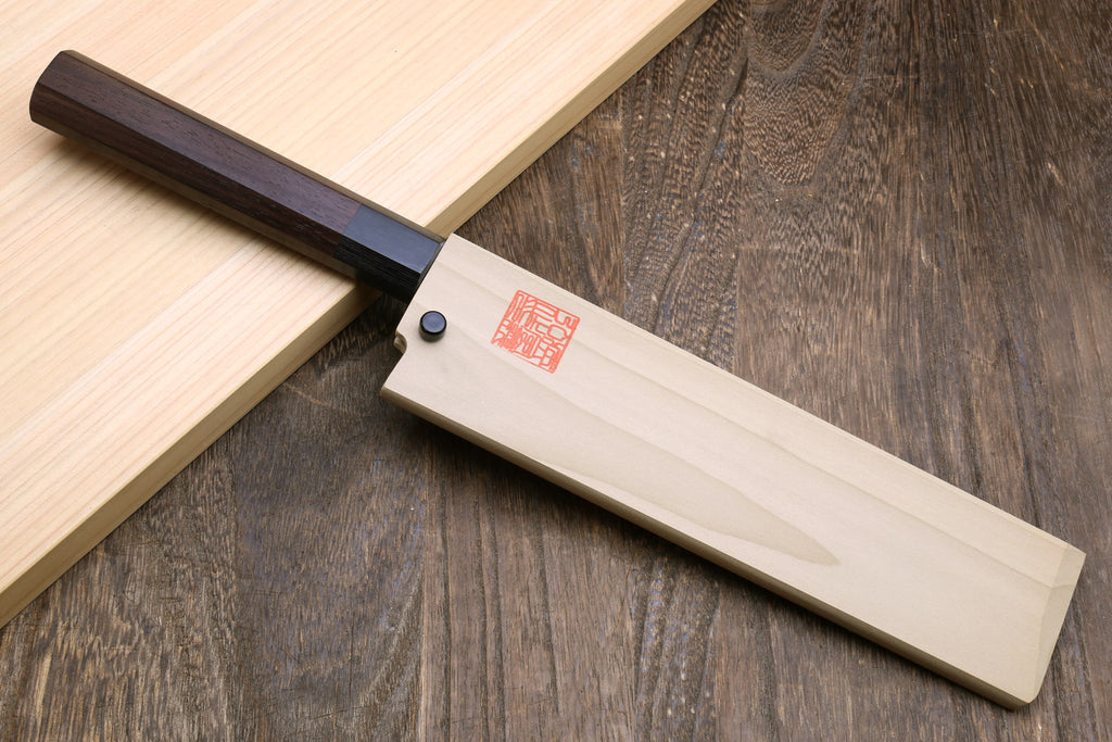 Japanese vegetable knife with pale steel blade and dark rosewood handle on board