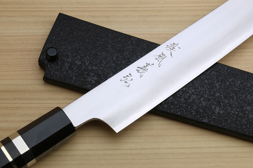 Kiritsuke slicer knife blade with etched characters and dark ebony handle on black saya