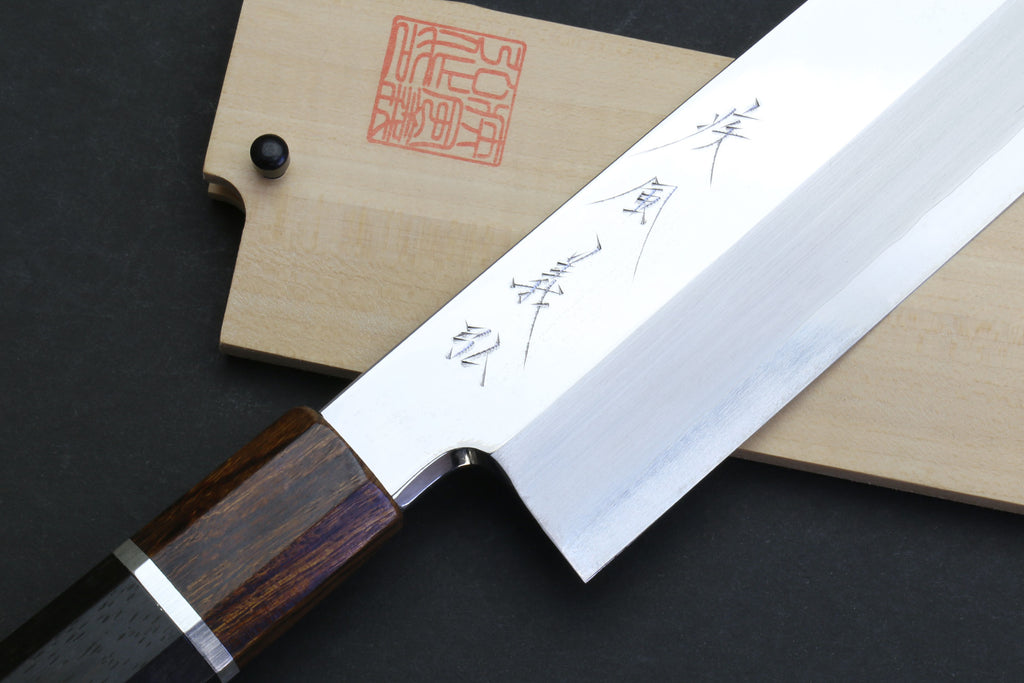 Japanese chef knife with mirror-polished blade, dark wood handle, wooden sheath