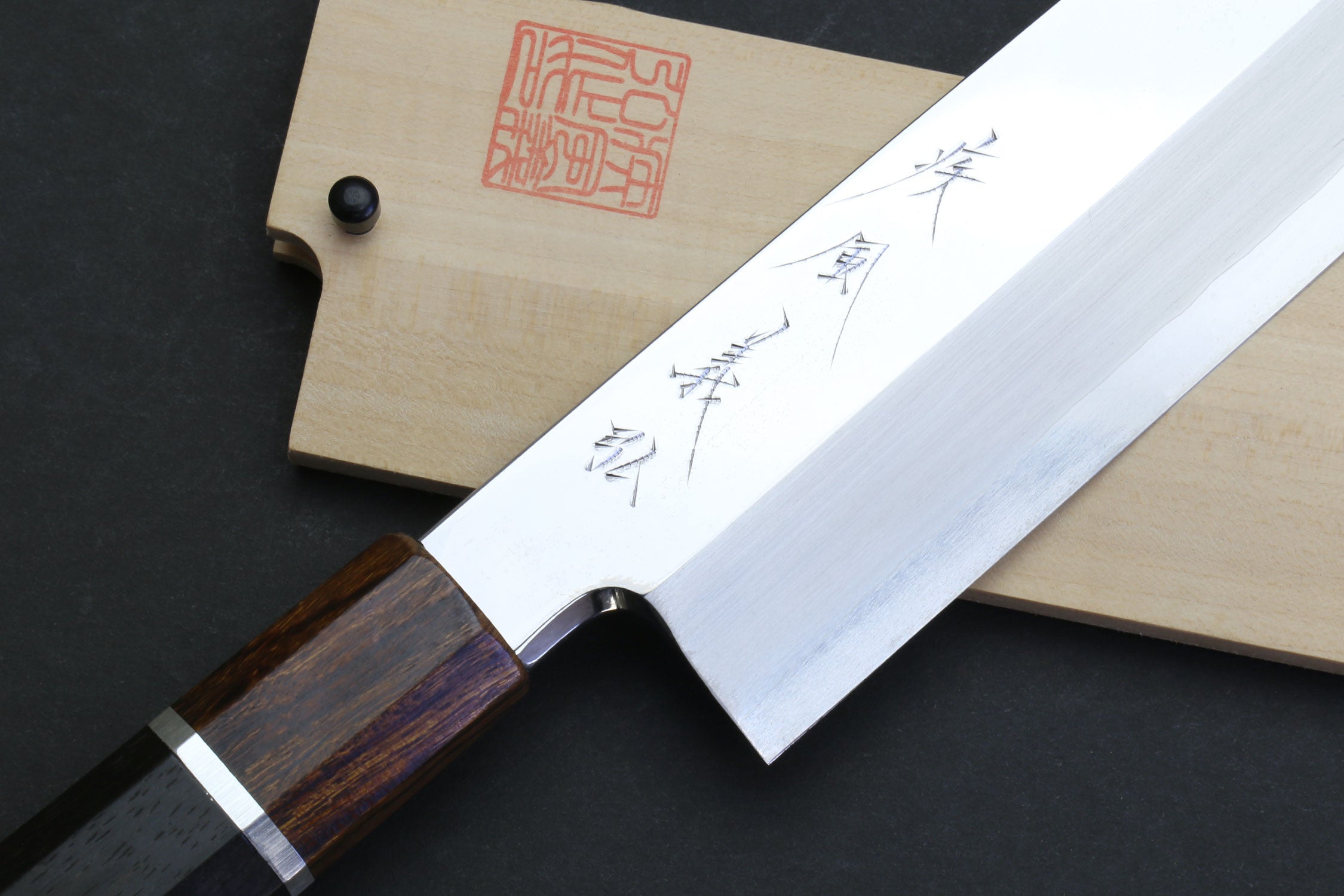 Japanese chef knife with mirror-polished blade, dark wood handle, wooden sheath