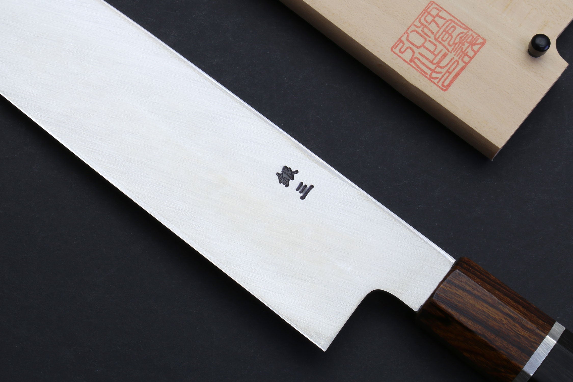 Japanese chef knife blade close-up with engraved markings, ebony handle
