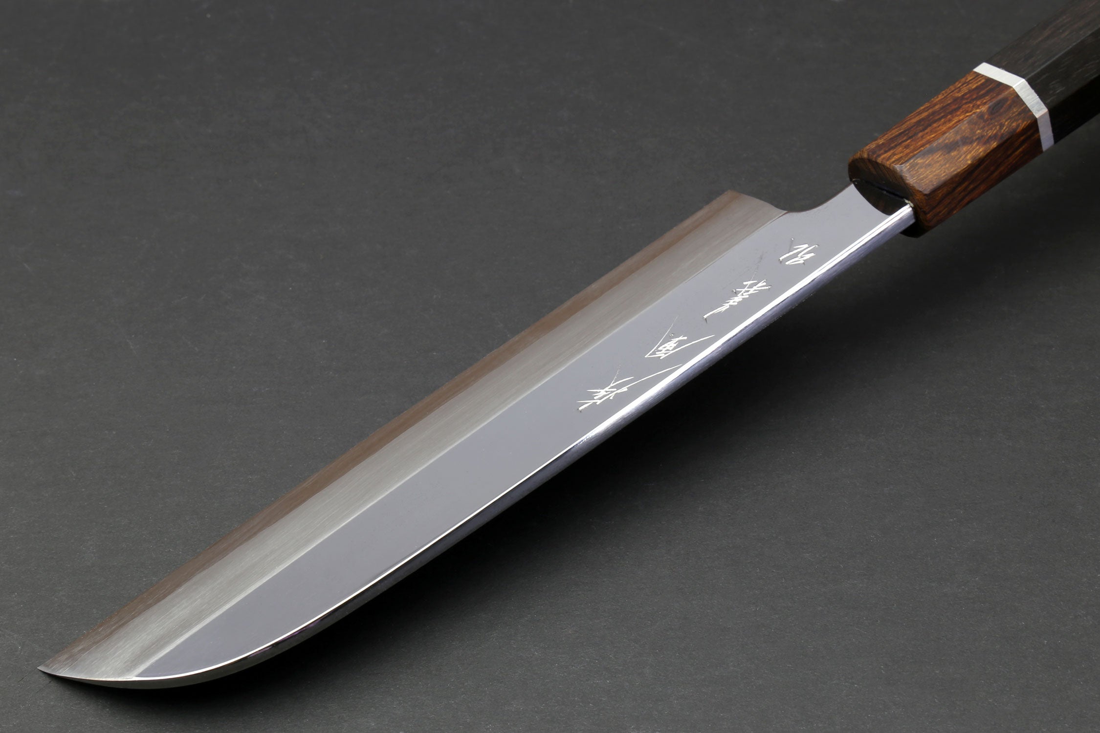 Japanese chef knife side view with mirror-polished blade and ebony handle