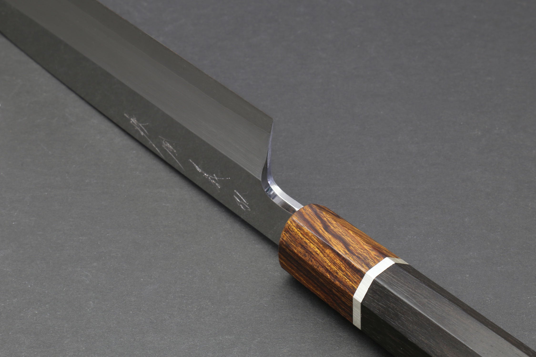 Japanese chef knife angled view with engraved blade and dark wood handle