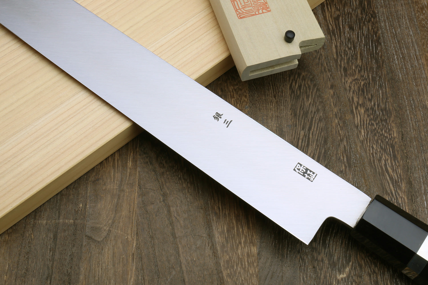 Mirror-polished tuna knife blade with Japanese markings and dark handle