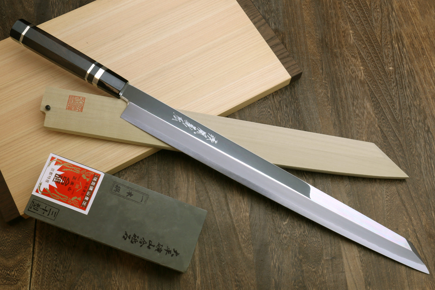 Yanagi-kiritsuke tuna knife with mirror blade, ebony handle, and pale wooden saya
