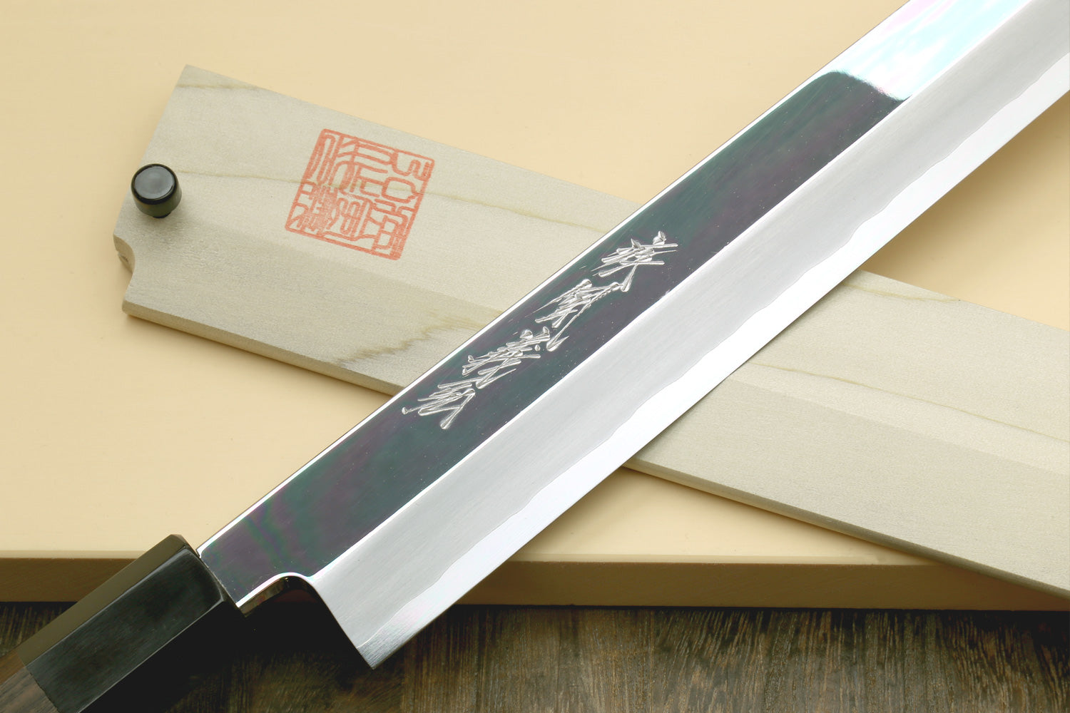 Japanese slicing knife with mirror-polished steel blade and ebony handle on sheath