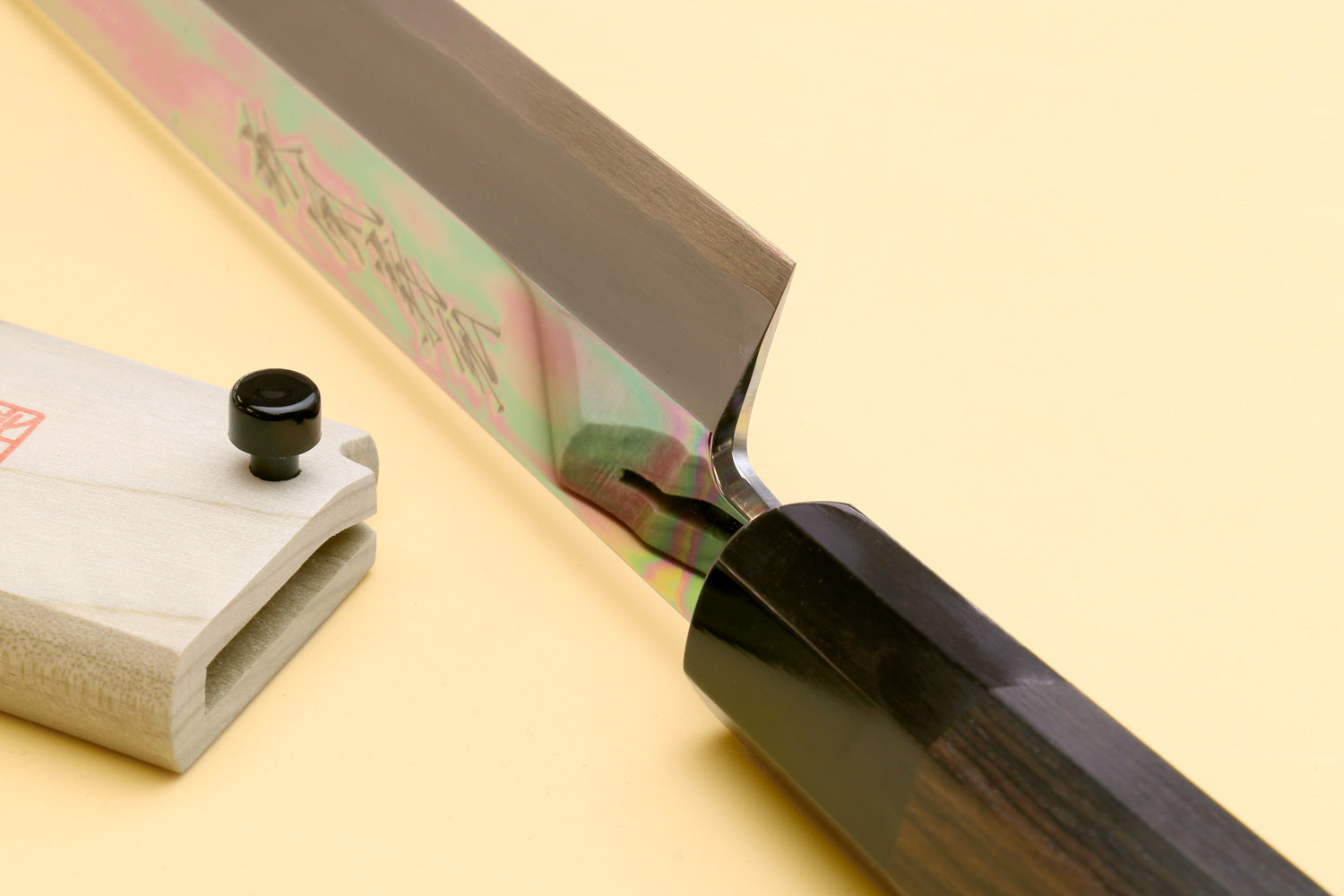 Japanese slicing knife with ebony handle, polished blade beside wooden sheath