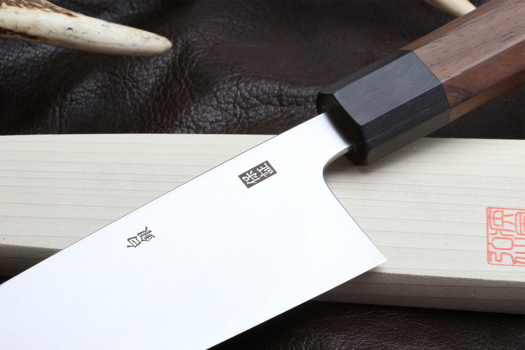 Japanese filet knife blade with stamped symbols and dark handle spacer