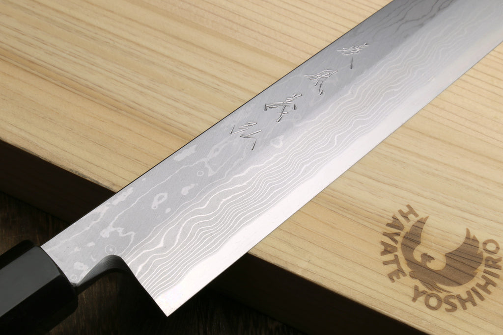 Japanese sushi knife with wavy Damascus blade and dark ebony handle.