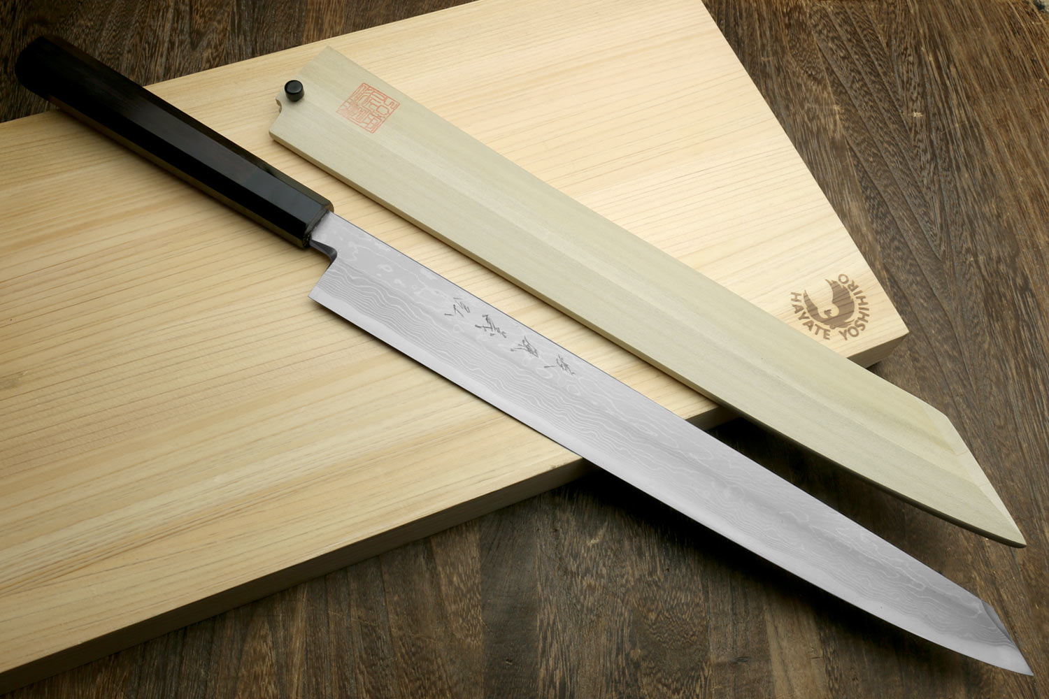 Japanese sushi knife with wavy blade, ebony handle, and black sheath.