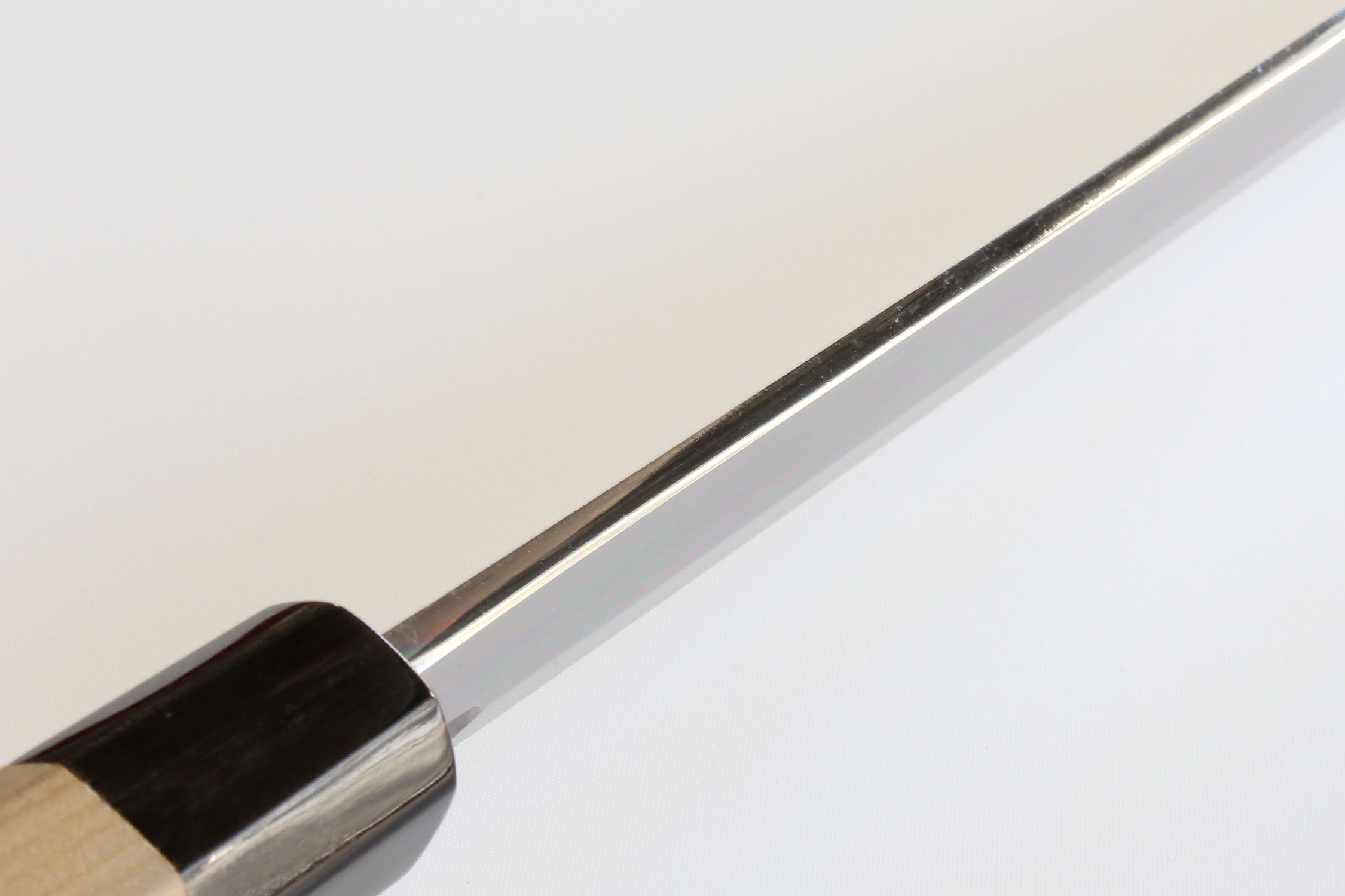 Tuna knife blade spine close-up with silver steel and light wood handle