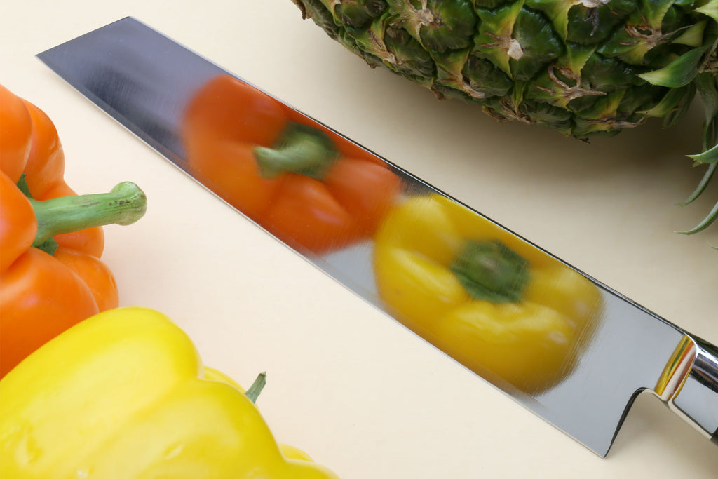 Chef knife with black pakkawood handle, silver blade over peppers