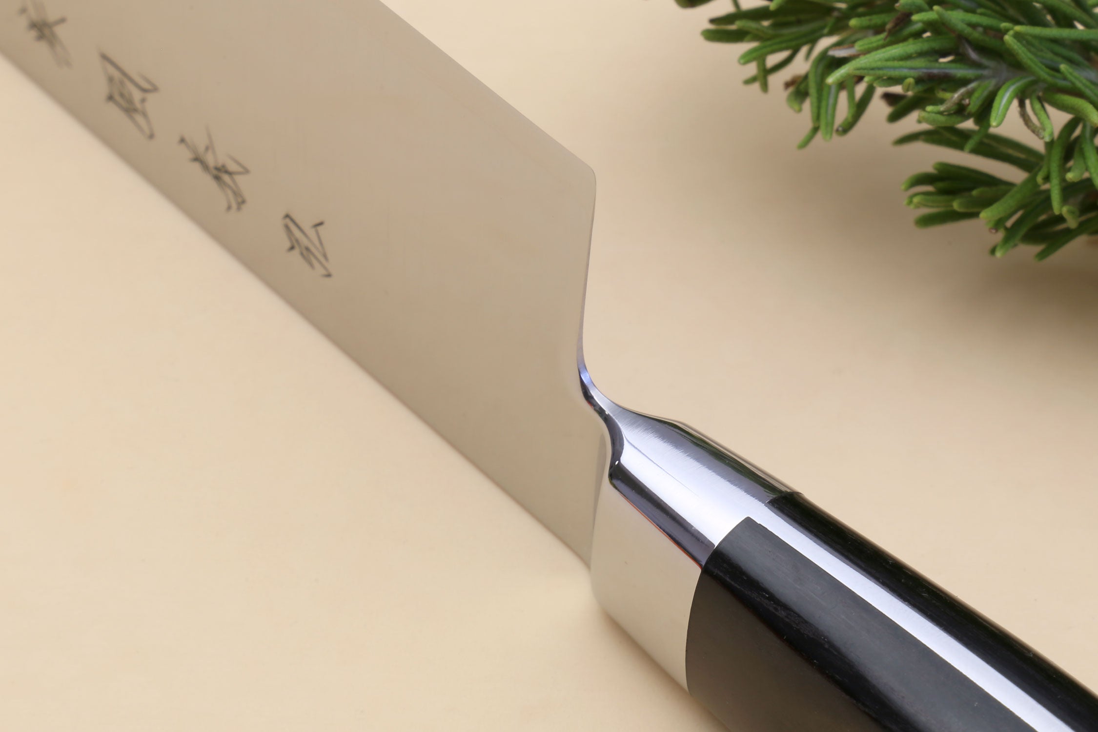 Kiritsuke chef knife heel close-up, silver blade with etched symbols and black handle