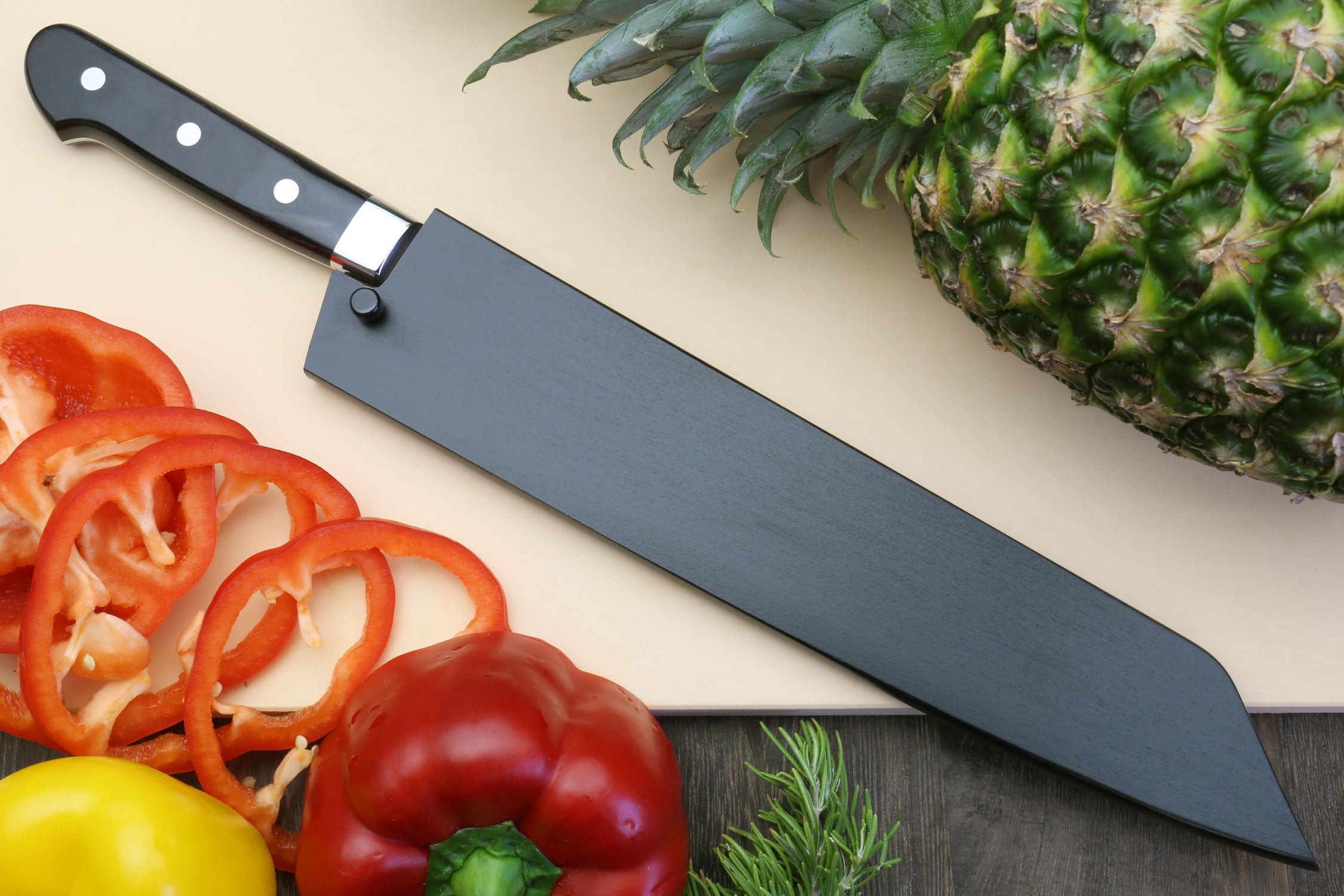 Kiritsuke chef knife with black handle, silver blade and fresh peppers