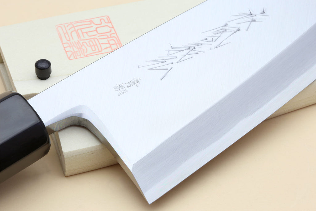 Deba chef knife blade close-up with etched marks and light wood handle
