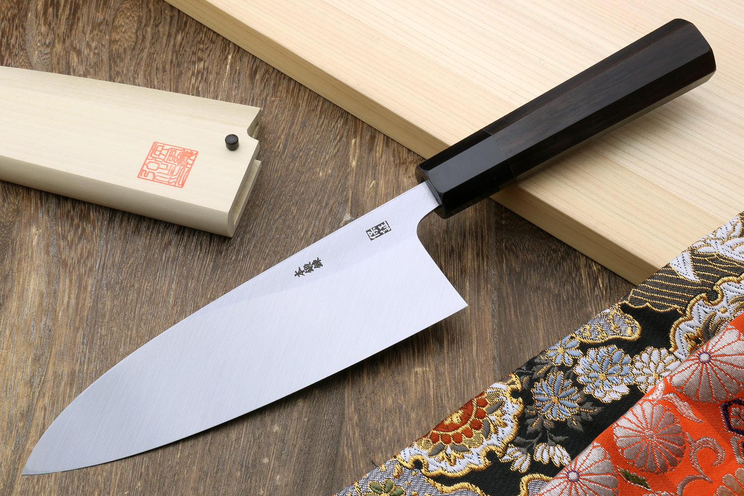 Deba fish fillet chef knife with dark steel blade and ebony handle on wooden board