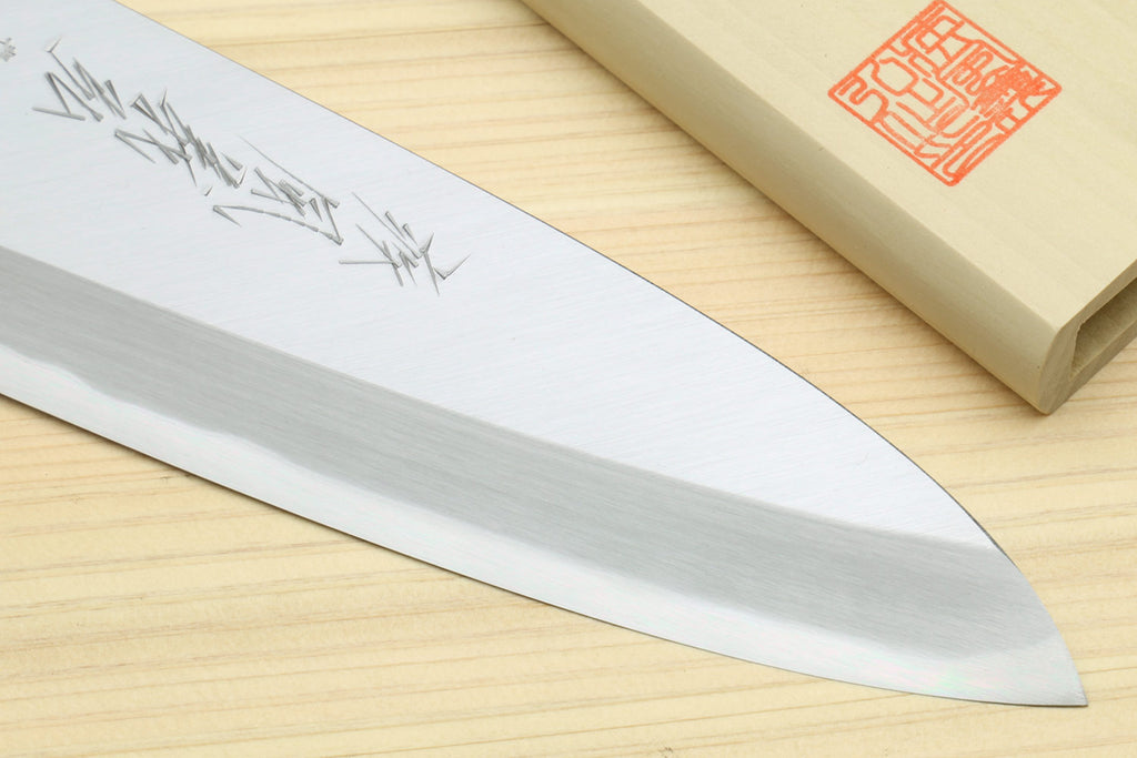 Deba knife blade tip close-up with engraved characters; black handle base