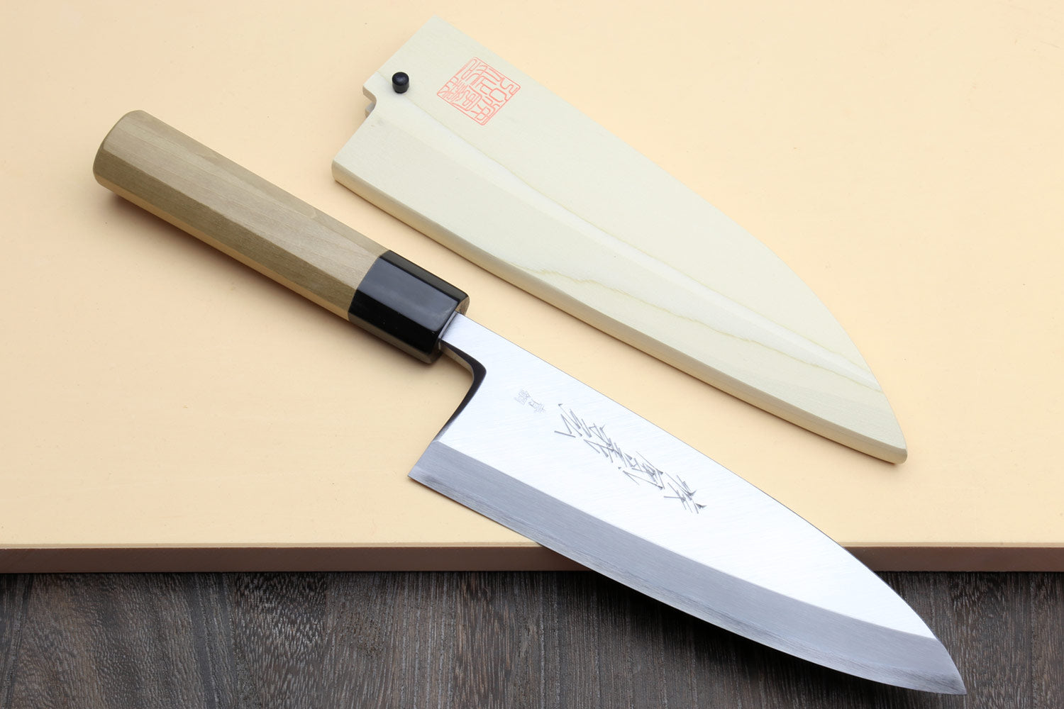 Deba chef knife with white blade and light wood handle, black bolster detail