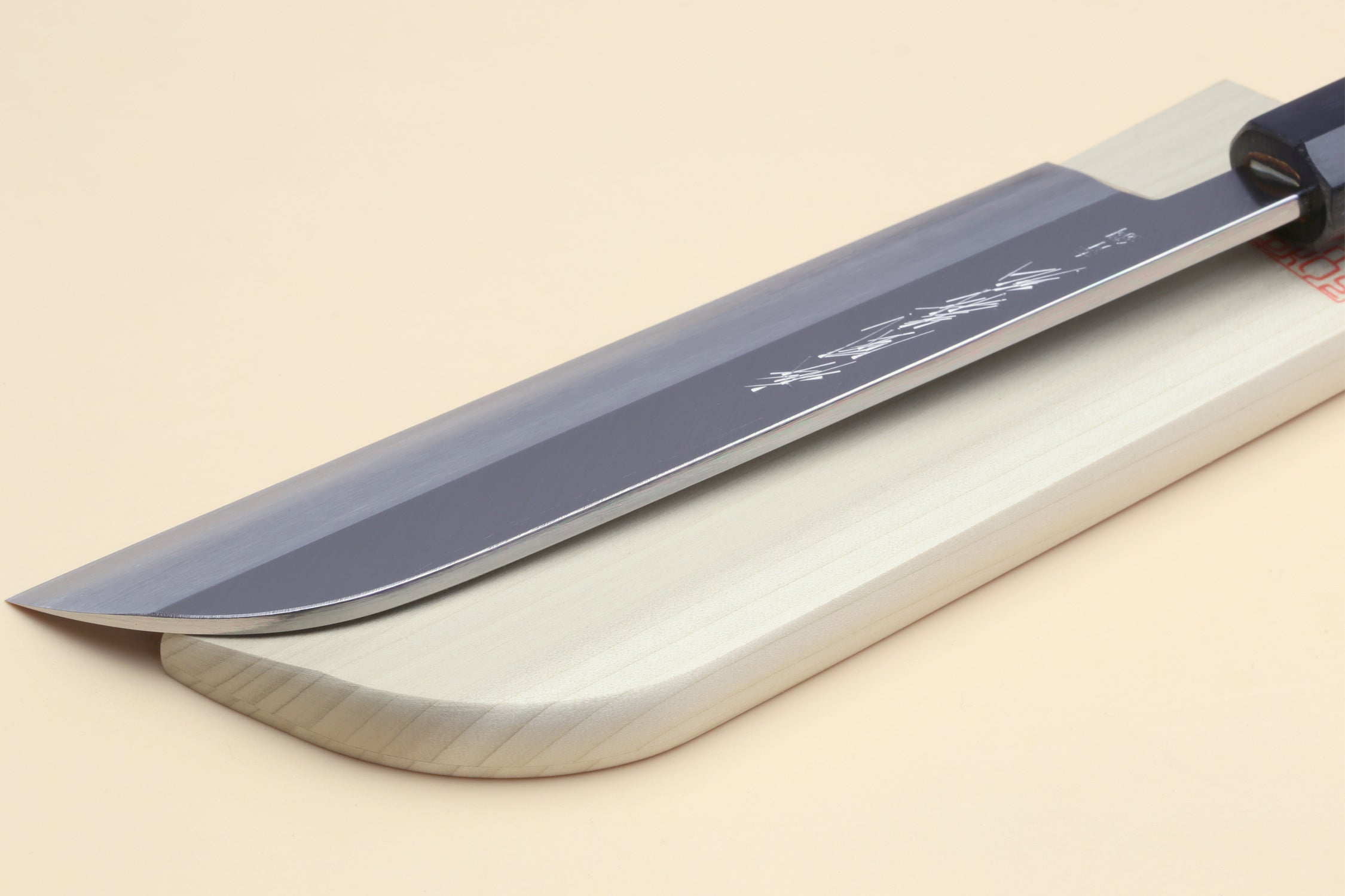 Blue steel Japanese vegetable knife on light wood saya, long curved blade and dark bolster