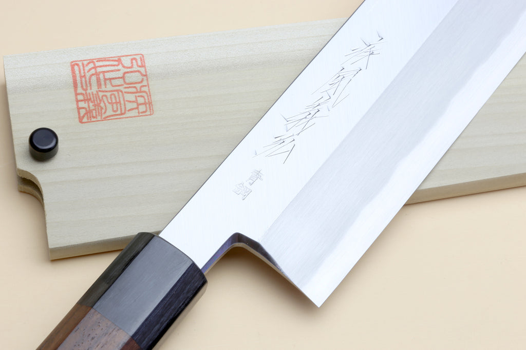 Japanese vegetable knife with rosewood handle beside light wood sheath, engraved blade art